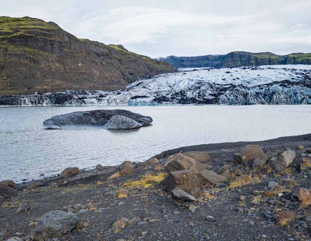 Pintoresco glaciar Solheimajokull en el sur de Islandia La lengua de este glaciar se desliza desde el volcán Katla Hermosa laguna glaciar con bloques de hielo y montañas circundantes