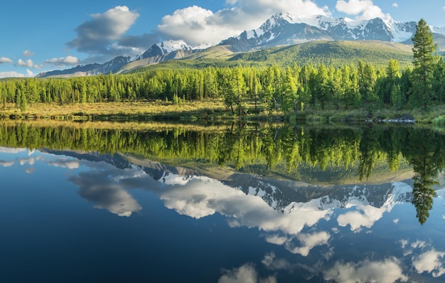 Pintoresco lago de montaña en la mañana de verano Altai Hermoso reflejo del cielo de las montañas y las nubes blancas