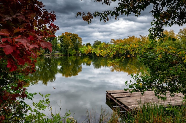 Pintoresco lago de otoño con un muelle de madera