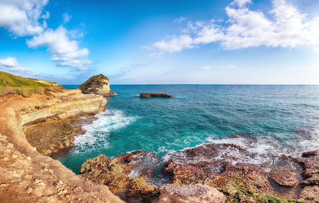 Pintoresco paisaje marítimo con acantilados rocosos blancos, islotes de bahía y faraglioni cerca de la playa de Spiaggia della Punticeddha