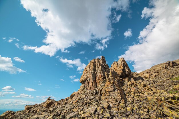 Pintoresco paisaje de montaña con valores atípicos de piedra en una colina rocosa a la luz del sol bajo un cielo nublado Paisaje colorido con rocas afiladas iluminadas por el sol en una montaña de piedra bajo nubes en un cielo azul con un clima cambiante