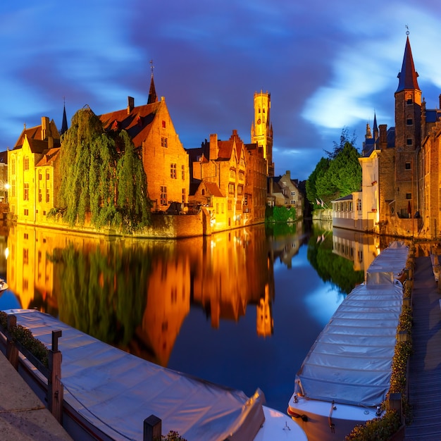 Pintoresco paisaje urbano con una ciudad de cuento de hadas medieval y la torre Belfort desde el muelle Rosario, Rozenhoedkaai, por la noche en Brujas, Bélgica