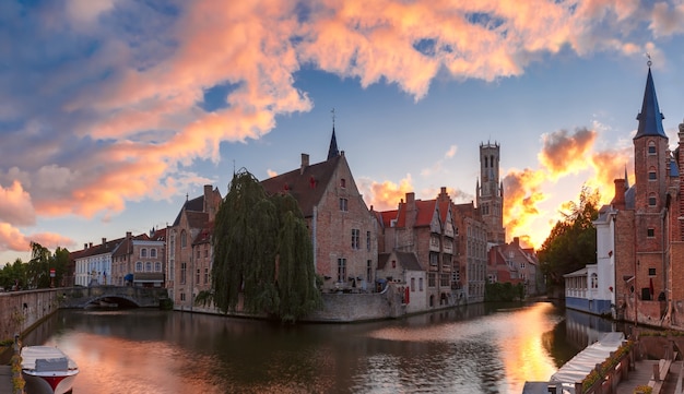 Pintoresco paisaje urbano con la torre Belfort y la Iglesia de Nuestra Señora desde el muelle Rosario, Rozenhoedkaai, al atardecer en Brujas, Bélgica