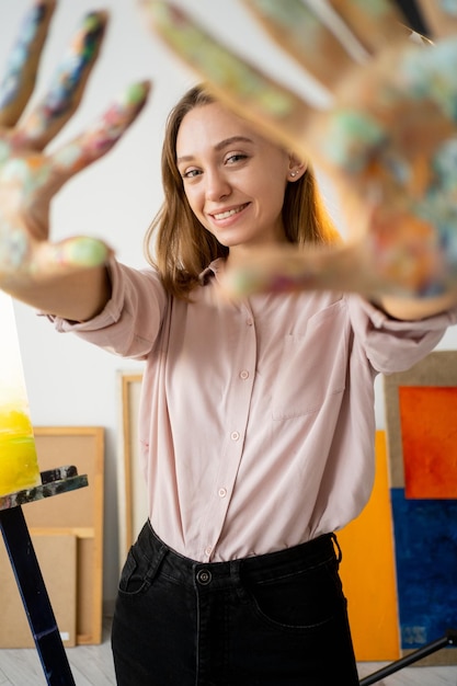 Pintura a dedo Pintor artista Estilo de vida criativo Retrato de mulher sorridente feliz com palmas sujas coleção de arte abstrata colorida na oficina em casa