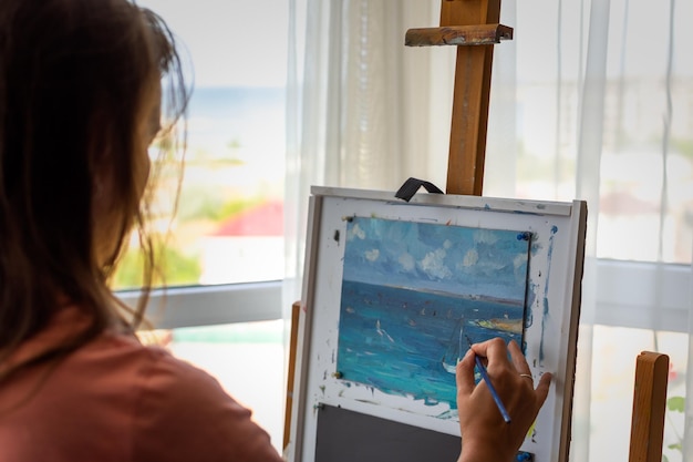 Pintura a óleo do artista. Uma jovem talentosa pinta um quadro no estúdio. O conceito de criatividade