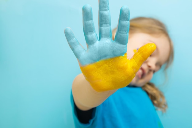 Pintura amarilla y azul en la mano de una niña Concepto de símbolos de bandera ucraniana