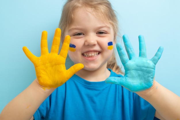 Pintura amarilla y azul en las palmas de los niños Concepto de símbolos de bandera ucraniana Chica ucraniana feliz