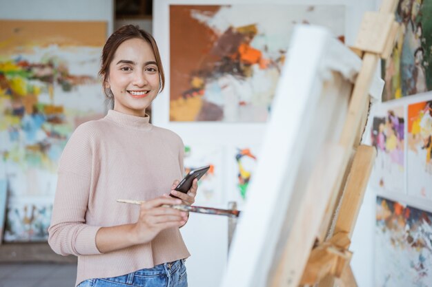 Pintura de artista femenina sujete el teléfono mientras trabaja