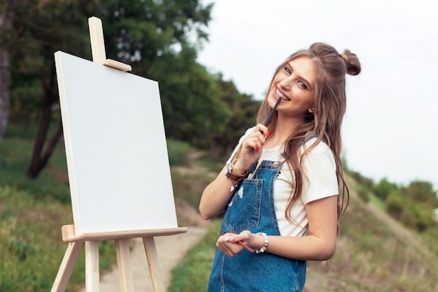 Pintura caucásica joven de la mujer en lona afuera