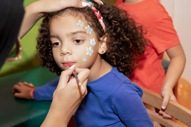 Pintura de rosto de uma menina com cabelo encaracolado