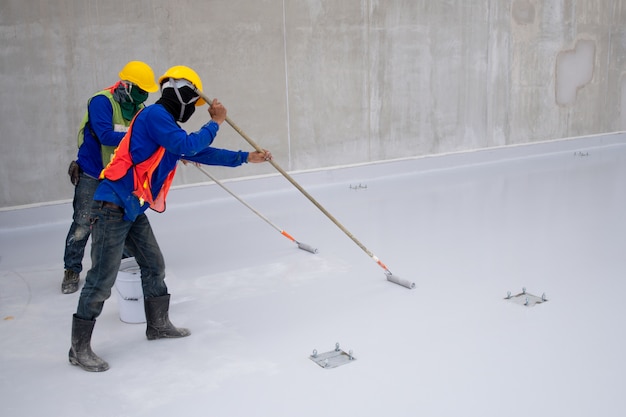 Foto pintura epoxy do trabalhador da construção no assoalho para a proteção da prova da água