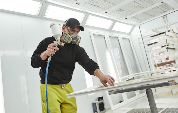 Pintura hecha al hombre correcto en la máscara del respirador pintar tablones de madera en el taller