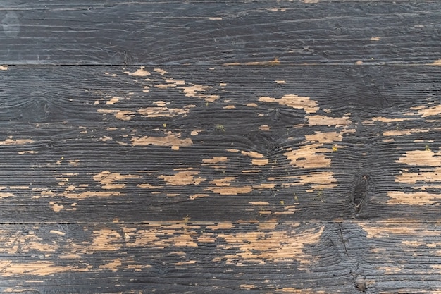La pintura negra se desprendió de los tablones de madera antiguos, revelando el color claro de la madera.