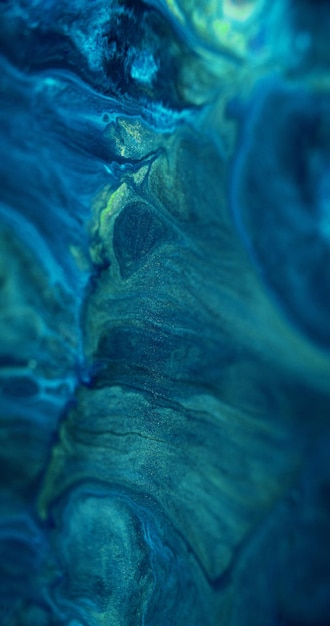 La pintura de onda brillante líquida se derrama con partículas de brillo brillante de color azul desenfocado mezcla de pigmento de tinta acrílico