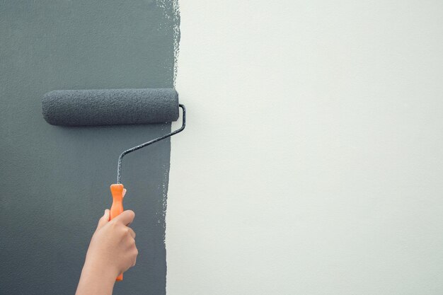 Foto pintura con pincel de rodillo trabajador pintando en la pared de la superficie pintura de apartamento renovando con pintura de color gris dejar el espacio de copia vacío blanco para escribir texto descriptivo al lado
