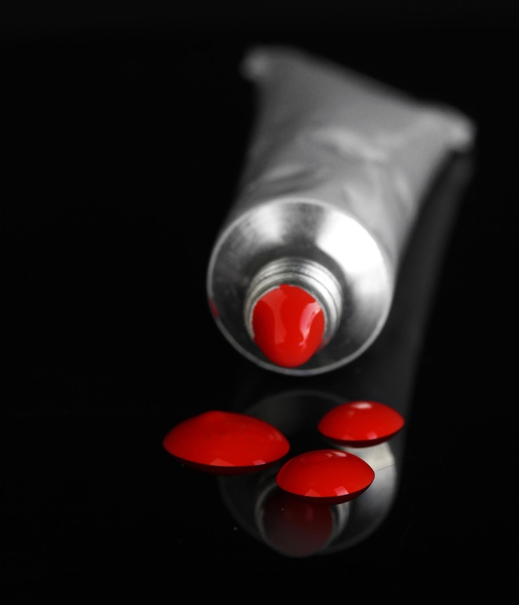 Foto la pintura roja sigue del tubo en primer plano de fondo negro