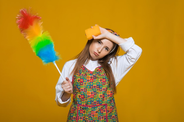 Pinup-Frau hält Suppenflaschen-Staubtuch Pinup-Frau mit glücklichem Gesicht auf gelbem Hintergrund