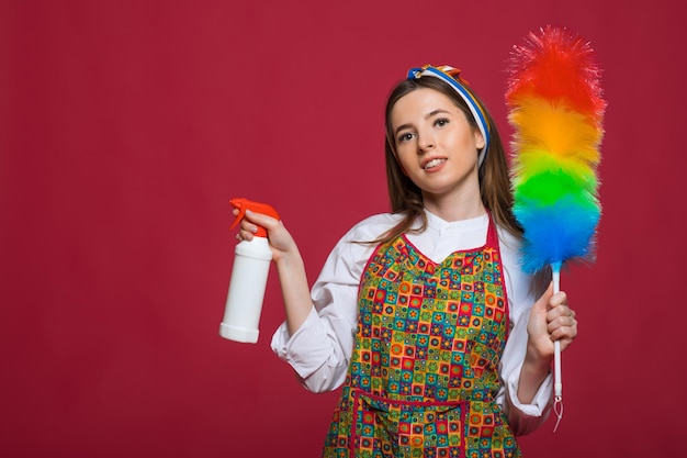 Pinup-Frau hält Suppenflaschen-Staubtuch Pinup-Frau mit glücklichem Gesicht auf rosa Hintergrund