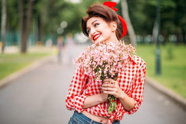 Pinup Mädchen mit Blumenstrauß, Retro amerikanische Mode. Nette lächelnde Frau im Pin-up-Stil