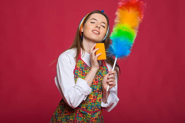 Pinup mujer sostenga sopa botella plumero pinup mujer con cara feliz sobre fondo rosa