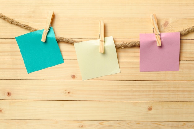 Pinza para la ropa colgada con papel en blanco sobre mesa de madera