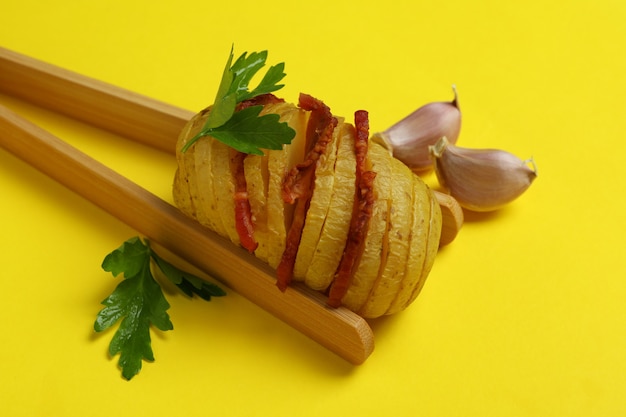 Pinzas de madera con patata al horno sobre fondo amarillo.