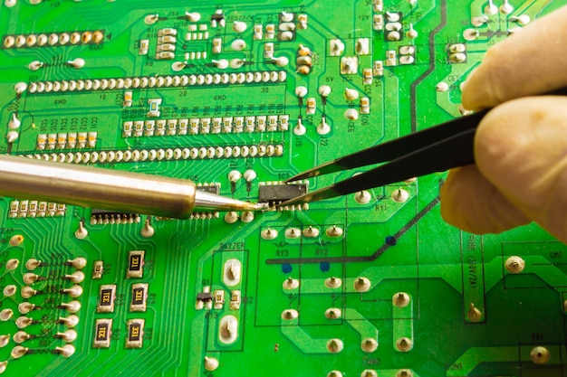 Pinzas con microchip y soldador Concepto de reparación de computadoras