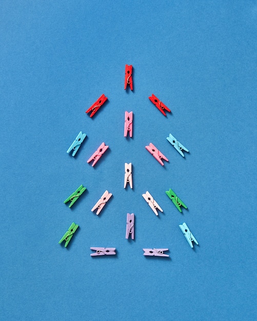 Pinzas para la ropa multicolores en forma de árbol de navidad en azul con espacio de copia. Vista superior.
