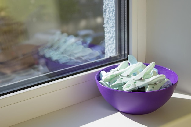 Pinzas para la ropa en un recipiente morado en el alféizar de una ventana