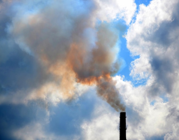 Pipa con humo espeso y las nubes del cielo