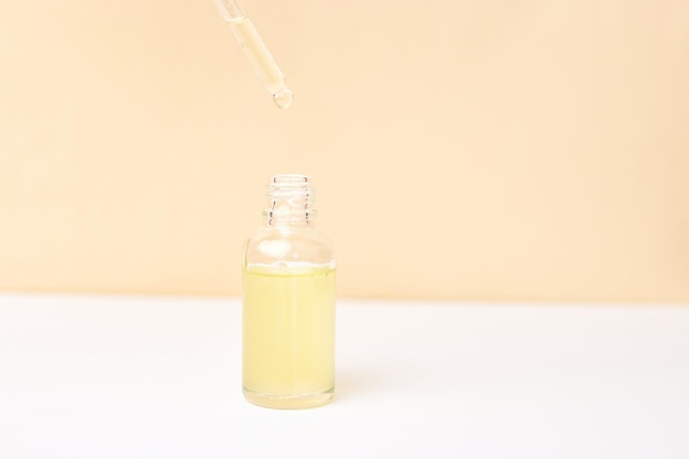 Pipeta com óleo essencial sobre garrafa em fundo branco e amarelo Conceito de medicina natural Aromaterapia