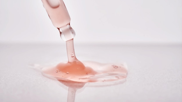 Foto pipeta com um close-up cosmético rosa viscoso