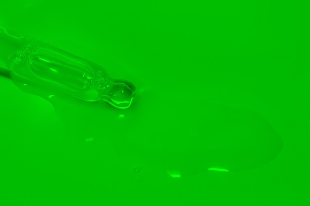Pipeta cosmética con goteo de aceite líquido y gotas sobre un fondo verde suero suero gel vitamina agua aceite Cosmético natural