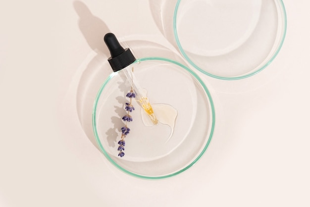 Pipeta de soro cosmético em uma placa de petri de cor lavanda clara sobre um fundo bege. cosmetologia, produtos farmacêuticos. peeling de ácido, óleo facial, colágeno.