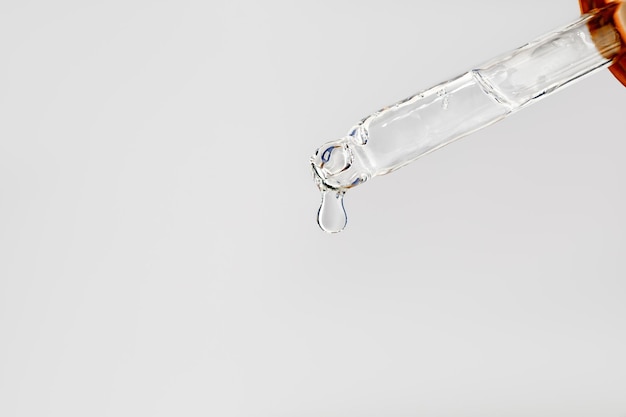 Foto pipeta con gota de aceite ácido hialurónico o colágeno para fondo gris spa minimalistic close up