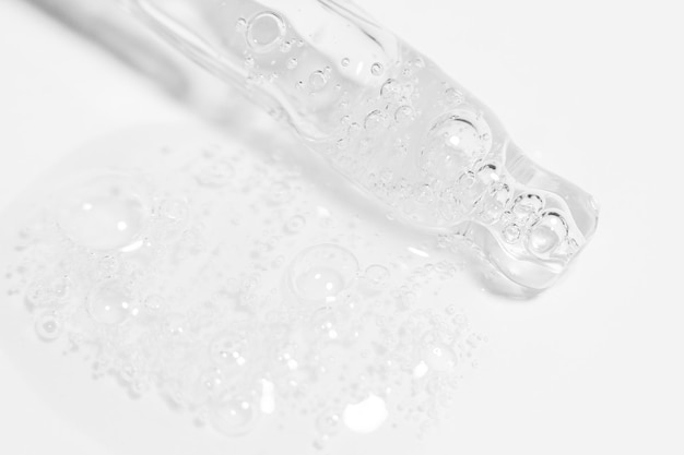 Pipeta transparente com gel ou líquido fluindo com bolhas em um fundo claro