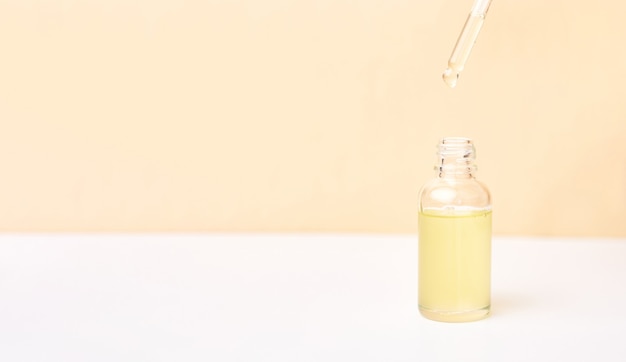 Foto pipetee con aceite esencial sobre la botella sobre fondo blanco y amarillo. concepto de medicina natural. aromaterapia