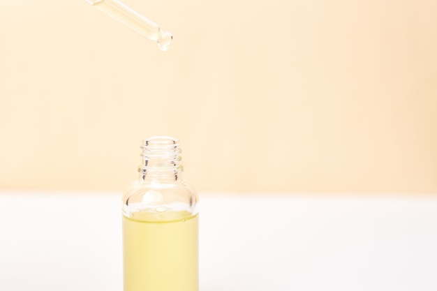 Pipetee con aceite esencial sobre la botella sobre fondo blanco y amarillo. Concepto de medicina natural. Aromaterapia
