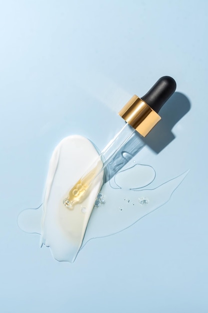 Pipette mit flüssiger Retinolsäure und kosmetischem Abstrich auf blauem Hintergrund Kosmetik- und Gesundheitskonzept Nahaufnahme Dosis von Serum-Retinol mit Luftblasen Flache Lage Präsentation von Luxus-Beauty-Produkten