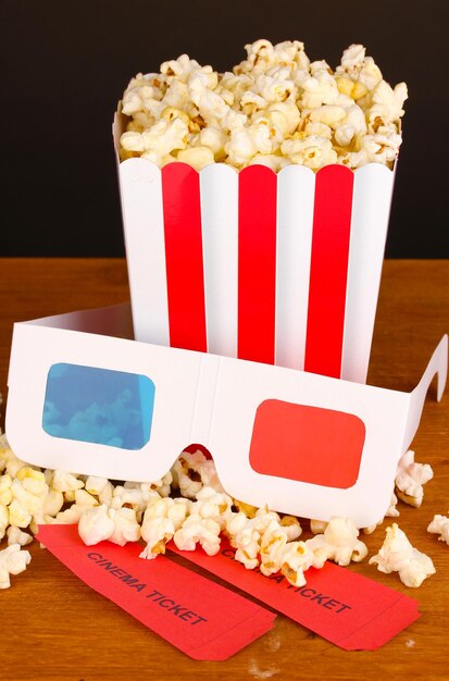 Pipoca com ingressos e copos de cinema na mesa de madeira em fundo marrom
