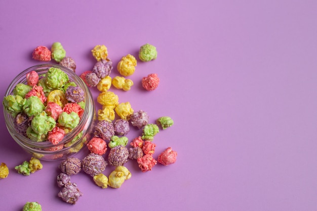 Pipoca com sabor de frutas multicoloridas em copos de vidro no fundo rosa. Pipoca doce revestida.