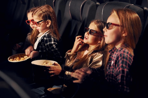 Pipoca deliciosa Grupo de crianças sentadas no cinema e assistindo filme juntos