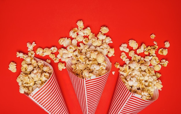 Pipoca derramada em sacos de papel em um filme de cinema de fundo vermelho entretenimento e imagem de conceito de carnaval