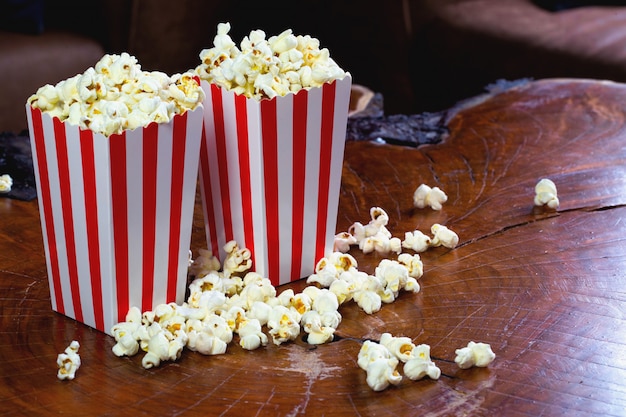 Pipoca em caixa de papelão listrada retrô vermelha e branca para cinema em mesa de madeira