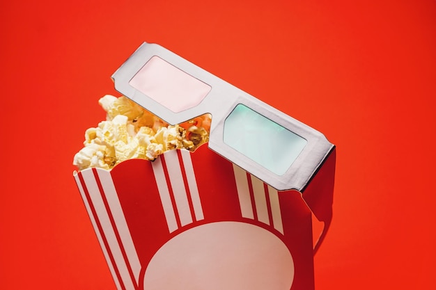 Pipoca em uma caixa com filmes de cinema de óculos 3D e imagem de conceito de entretenimento