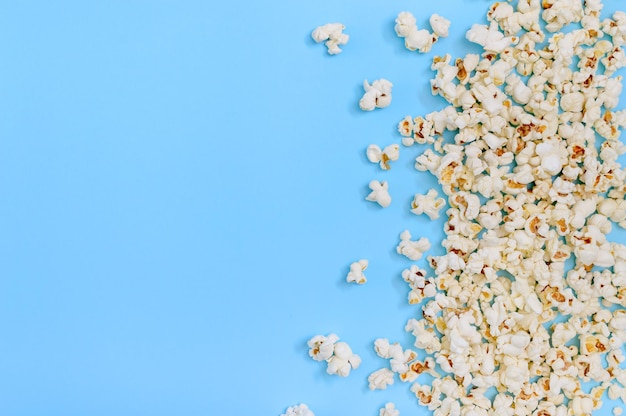 Pipoca salgada saborosa espalhada sobre fundo azul com espaço de cópia Filmes de cinema e conceito de entretenimento