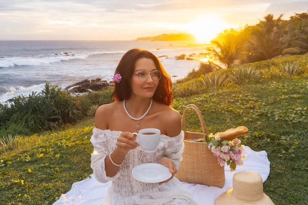 Piquenique de café da manhã na hora do chá com mulher romântica em vestido branco