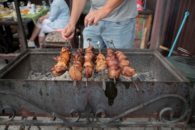 Piquenique de churrasco com kebabs e carne em fogo aberto em um dia de verão no quintal de uma casa particular