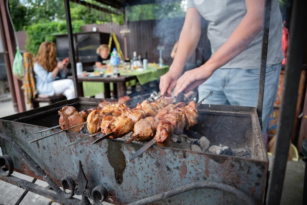 Piquenique de churrasco com kebabs e carne em fogo aberto em um dia de verão no quintal de uma casa particular