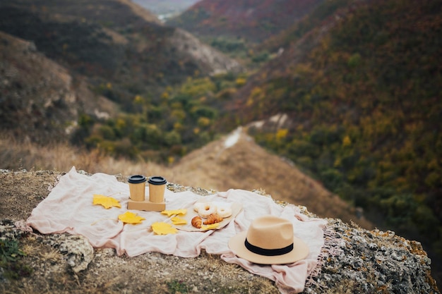 Piquenique de outono com café de copos de papel e rosquinhas nas montanhas